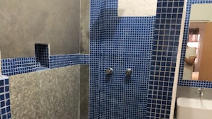 Baño con zona de ducha, paredes con azulejos y un lavamanos.