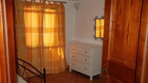 A bedroom with a bed, a bedside table, a dresser, and a mirror.
