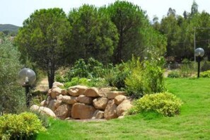 A garden with a stone wall, trees, and a lamp post.