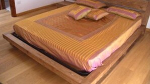 A single bed with a wooden frame and a mattress with a striped cover.