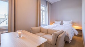 Una habitación de hotel con cama, sofá, mesa y ventana.