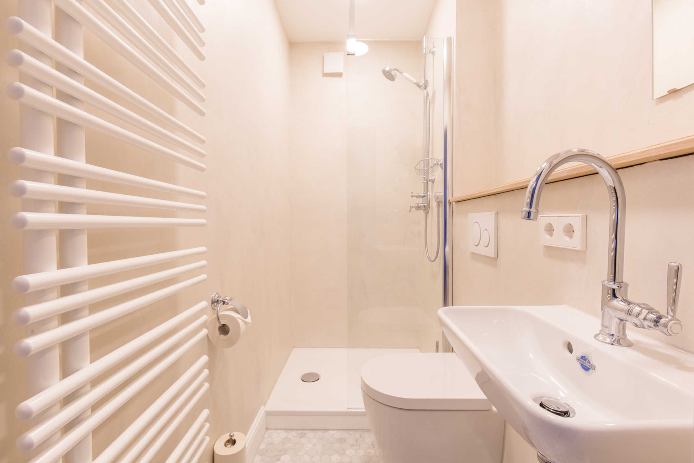 Ein Badezimmer mit weißer Toilette, einem Waschbecken mit Chromarmatur und einer Duschkabine mit Glastür.
