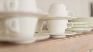 A wooden table with white ceramic cups and saucers.
