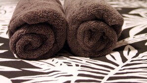 Un lit avec une couvre-lit à motifs et deux serviettes enroulées.
