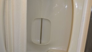 Une petite salle de bain avec une baignoire, des toilettes et une serviette accrochée au bord de la baignoire.