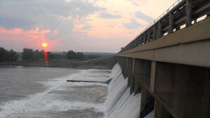 Un barrage avec de l’eau qui s’écoule par son déversoir au coucher du soleil.