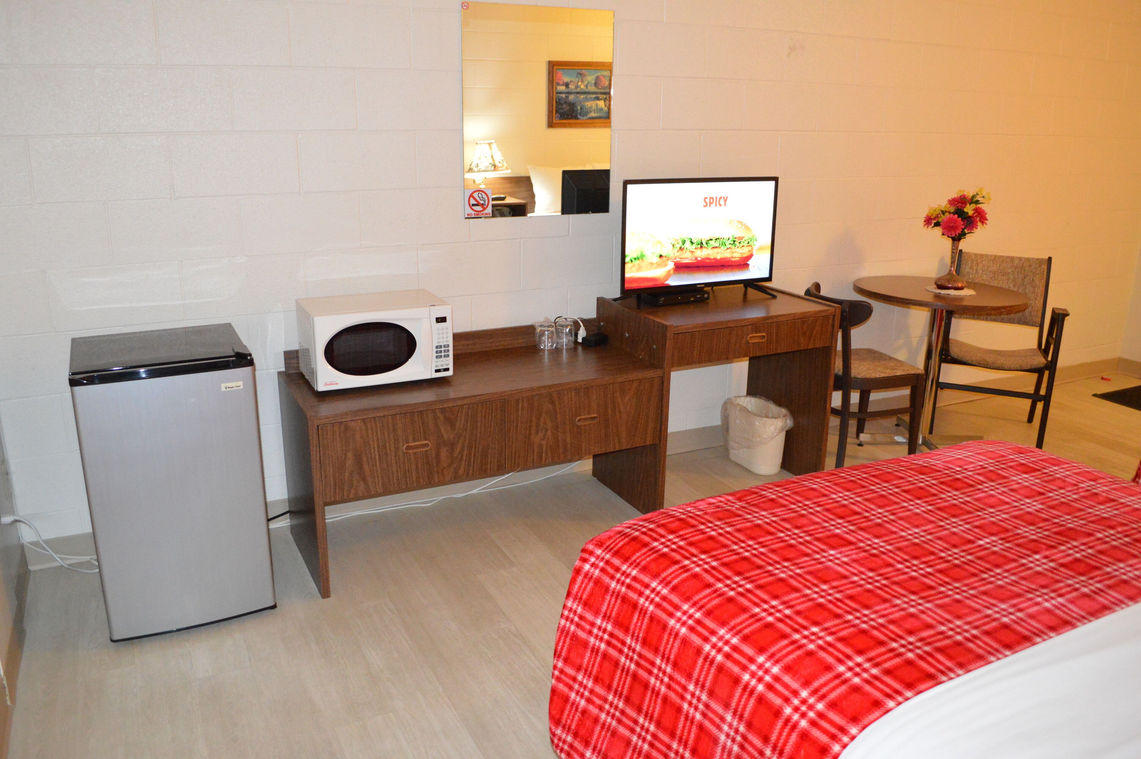 Une chambre d’hôtel compacte comprenant un lit, un bureau avec un ordinateur, un four à micro-ondes et un petit réfrigérateur.