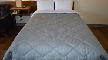 A bed with a quilted blanket, a bedside lamp, and a telephone on a wooden nightstand.