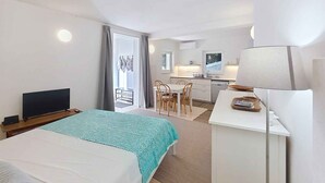A hotel room with a bed, a desk with a lamp, a TV, a balcony with a view, and a kitchenette. - Studio with terrace for 2 people (Baška)