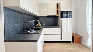 A modern kitchen with black marble countertops, white cabinetry, and a built-in oven.