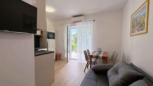 A compact living space with a kitchenette, a dining area, and a sofa.
