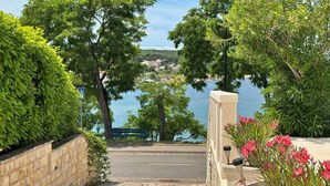 A stone pathway leading to a bench overlooking a body of water with trees and a clear sky.
