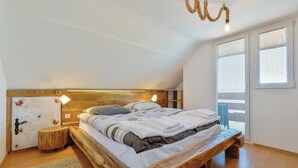 Una camera da letto con un letto in legno, una testiera rustica e un'ampia finestra con persiane.