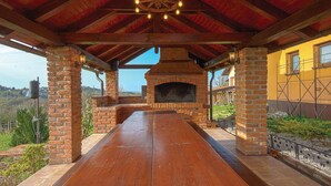 Un patio esterno in legno con un camino in mattoni, circondato da pilastri in mattoni e un tetto in legno.