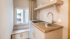 Une cuisine de taille réduite, dotée d’une fenêtre, d’un évier encastré et d’un plan de travail en bois.