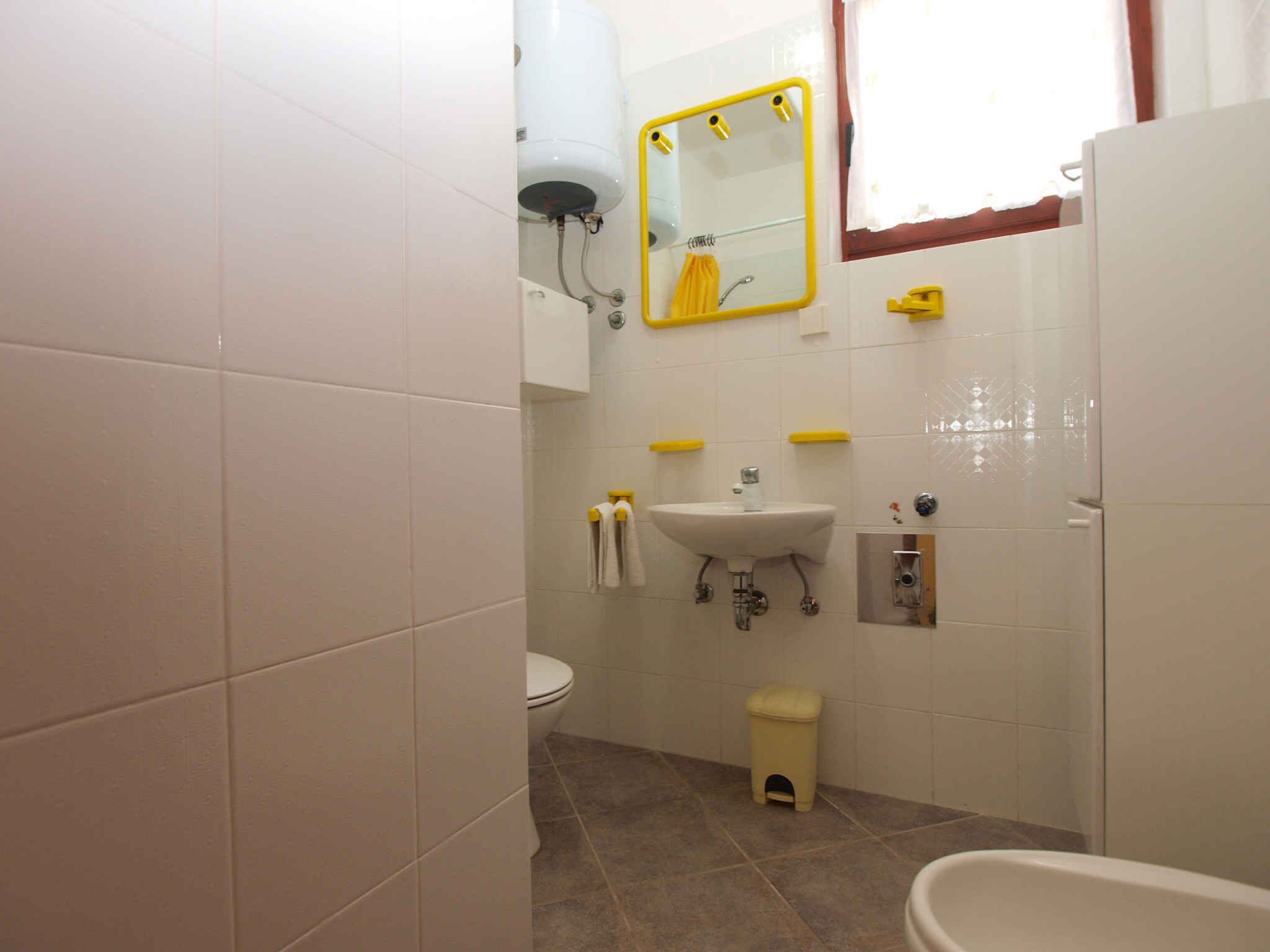 A bathroom with a toilet, sink, mirror, and a small stool.