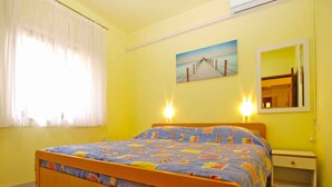 Ein Schlafzimmer mit einem hölzernen Bett, einem Nachttisch, einem Spiegel und einem Gemälde eines Piers an der Wand.