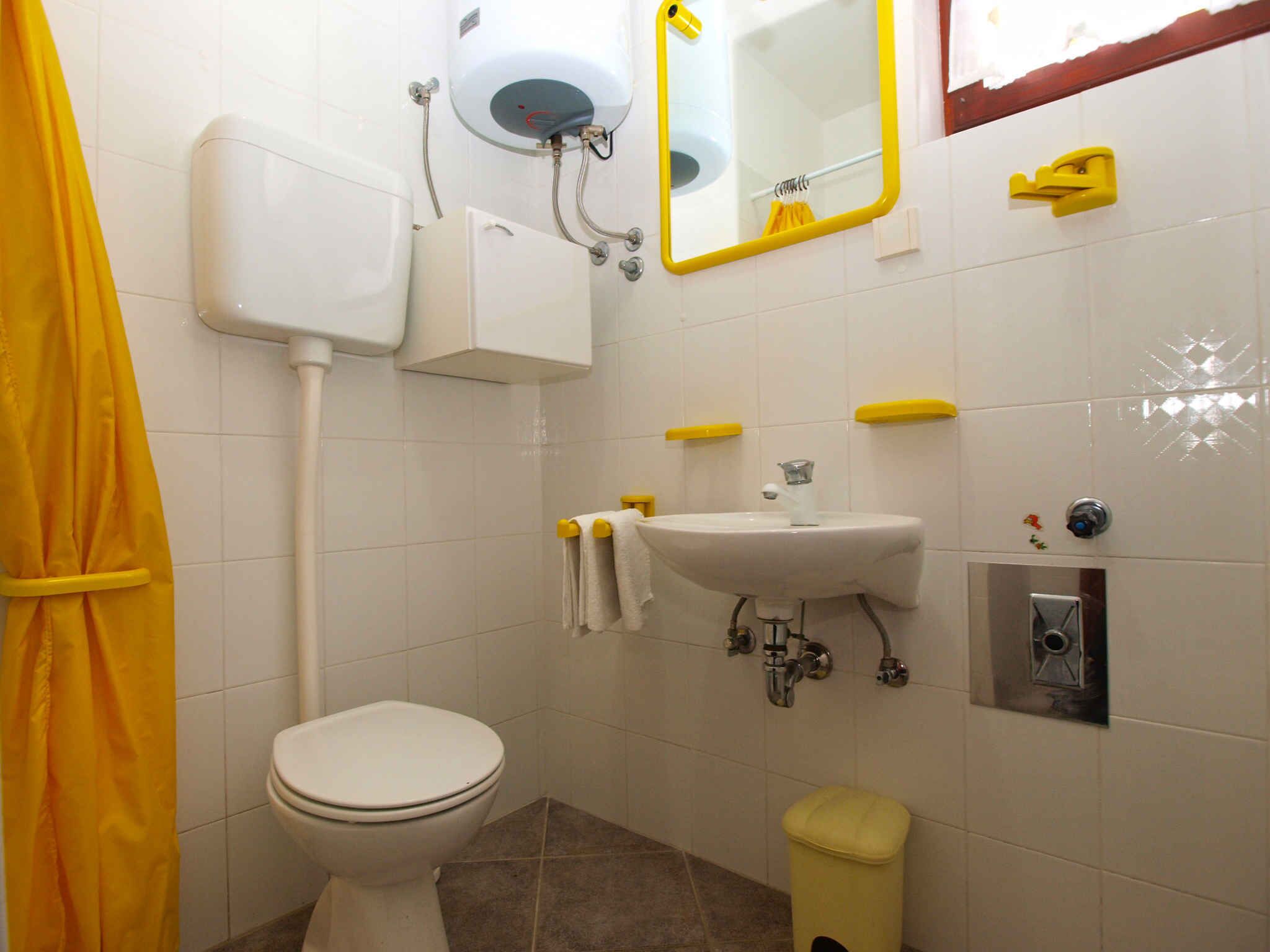 A bathroom with a toilet, sink, and mirror.