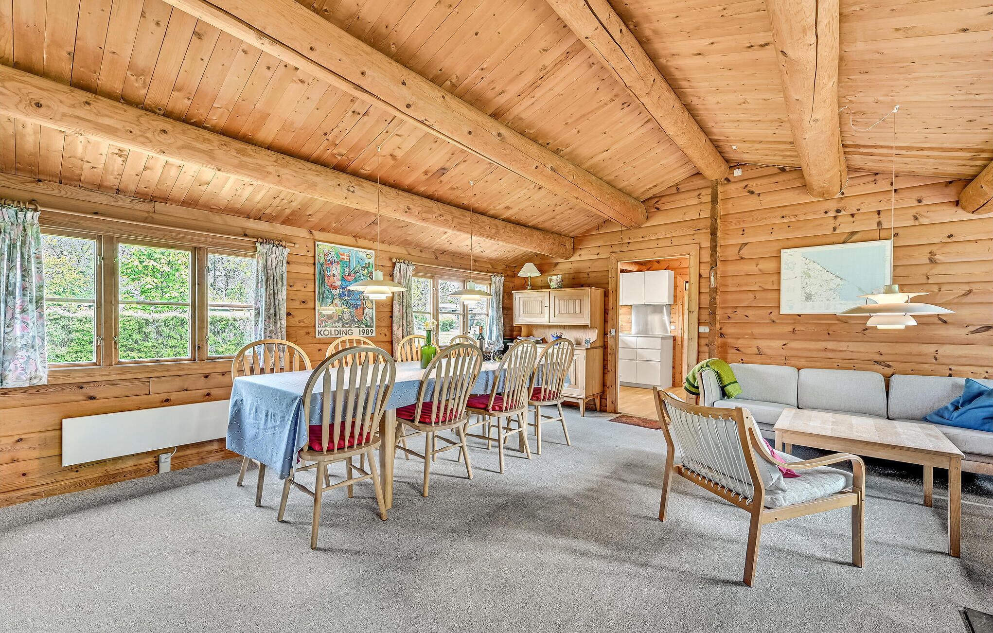 A wooden cabin interior with a dining area, kitchen, and seating area.