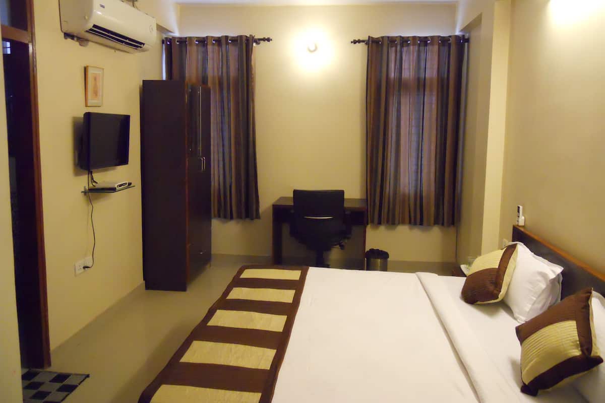 Une chambre d’hôtel avec un lit, un bureau, une chaise, une télévision et des rideaux.