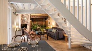 Un coin repas avec une table dressée pour quatre personnes, un canapé et un escalier.