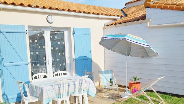 Eine Terrasse mit Tisch und Stühlen, einem blauen Sonnenschirm und einem Blumentopf.