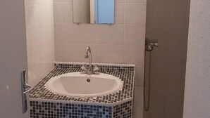 Ein Badezimmer mit einem weißen Waschbecken, einem Spiegel und einer Dusche.