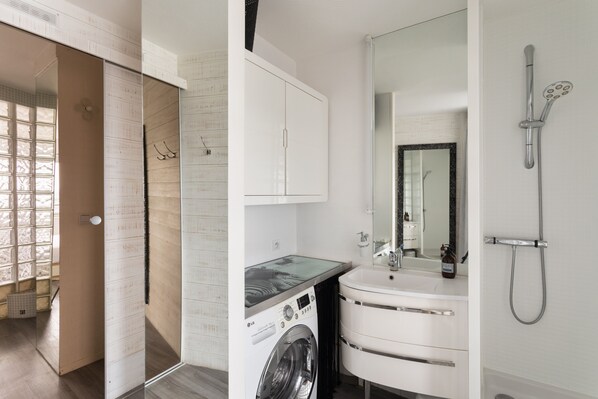 Un baño moderno con lavadora, lavamanos y ducha.