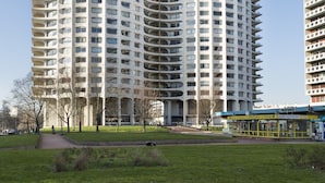 Un edificio de gran altura con fachada curva, múltiples balcones y un parque verde al frente.