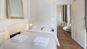 A hotel room with a bed, a mirror, a chair, and a wardrobe. - L'HORLOGE - Cocon de Charme au coeur de Rennes (Rennes)