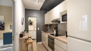 Une cuisine de taille réduite équipée d’un four à micro-ondes, d’une cuisinière et d’un évier.