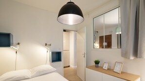 Une chambre à coucher moderne avec un lit, des tables de chevet, un miroir et une commode en bois.
