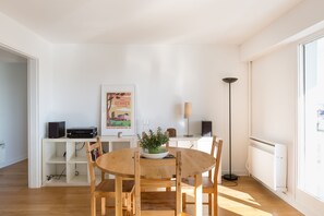A dining area with a round wooden table, chairs, a potted plant, a framed picture, a speaker, and a floor lamp. - TREGOR - 2 ch - Parking + Vue sublime (Rennes)
