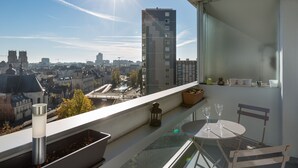 A balcony with a table and chairs, overlooking a cityscape with buildings and a river. - TREGOR - 2 ch - Parking + Vue sublime (Rennes)