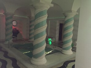 A lobby with striped columns, a staircase, and a pool area.