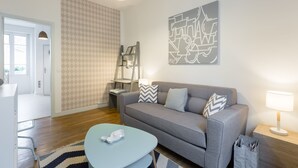 A modern living room with a grey sofa, a blue coffee table, and a patterned rug.