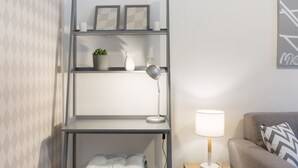 A modern room with a grey metal desk, a white lamp, a grey sofa, and a patterned wall.