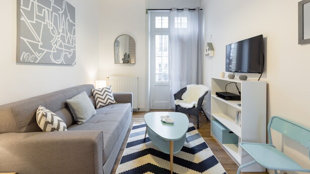 A modern living room with a sofa, a coffee table, a TV, and a bookshelf.
