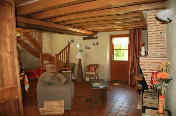 A cozy living room with a wooden staircase, a sofa, a coffee table, and a brick wall.