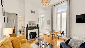 Una sala de estar moderna con chimenea, un sofá, un comedor y un televisor montado en la pared.