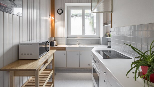 Et moderne køkken med hvide skabe, en mikroovn, en vask og en komfur.