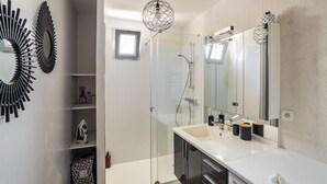 Une salle de bain moderne avec une douche à parois de verre, un lavabo blanc avec un miroir et des éléments décoratifs sur les murs.