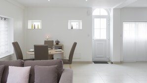 Ein modernes Wohnzimmer mit einem grauen Sofa, einem Esstisch mit Stühlen und einer Küche im Hintergrund.
