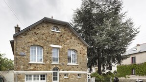 Ein Steinhaus mit Garage, einem Hydranten und einem Baum davor.