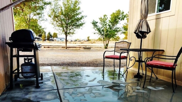 Une terrasse avec un barbecue, des chaises et une table.