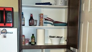 Une cuisine compacte équipée d’un four à micro-ondes, d’un réfrigérateur et d’une étagère de rangement.