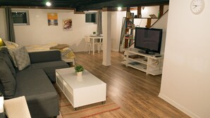 Ein modernes Wohnzimmer mit einem grauen Sofa, einem weißen Couchtisch und einem Fernseher auf einem weißen Schrank.