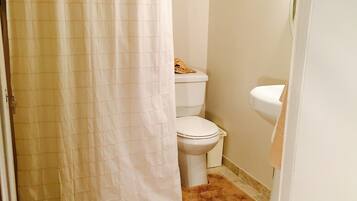 A bathroom with a shower curtain, a toilet, and a sink.
