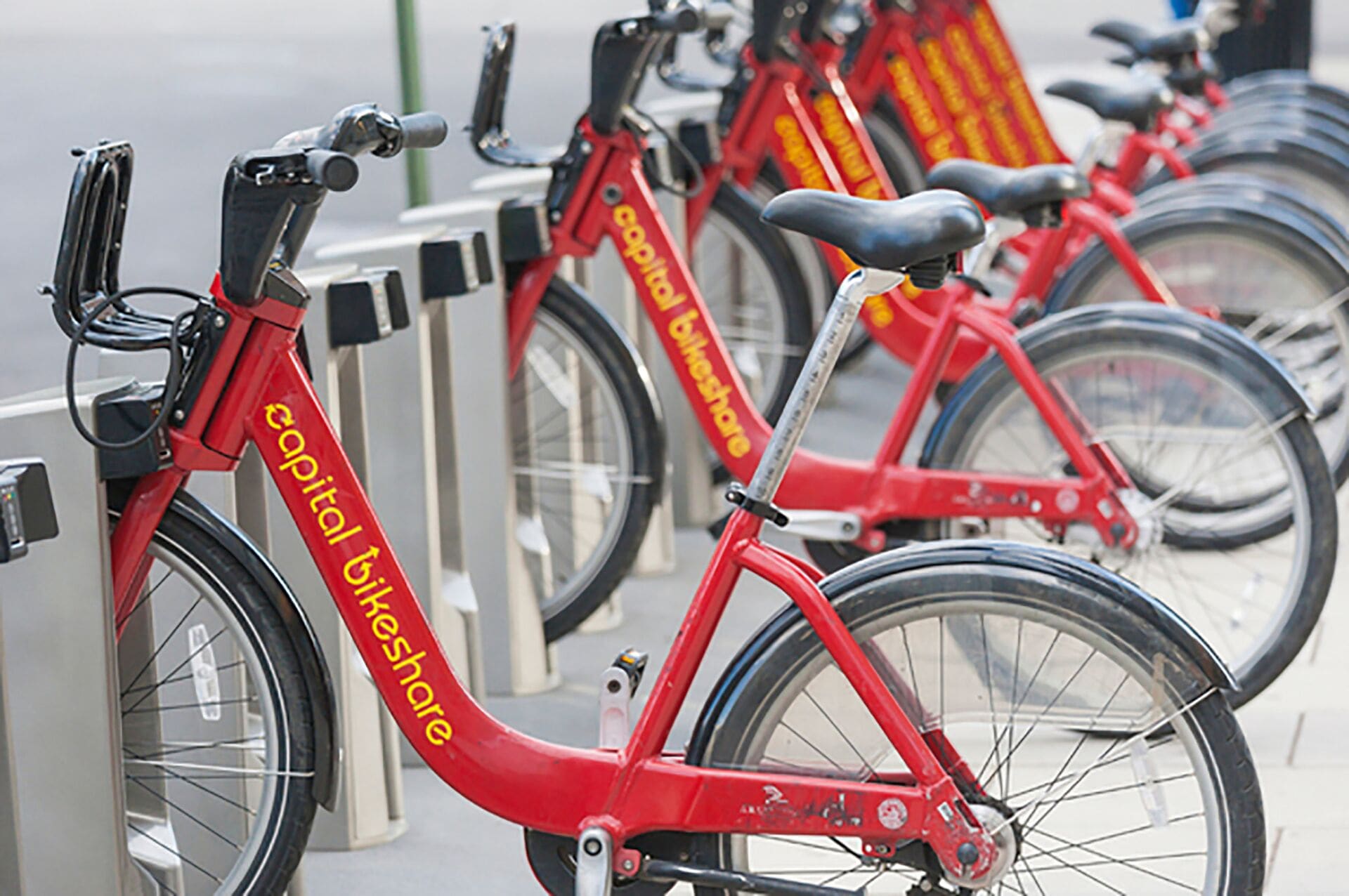 Une rangée de vélos rouges portant la marque « Capital Bikeshare » est stationnée devant une borne de vélos en libre-service.