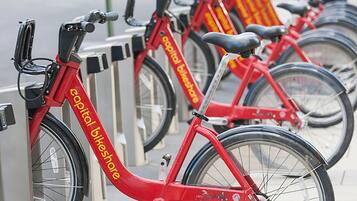 Une rangée de vélos rouges portant la marque « Capital Bikeshare » est stationnée devant une borne de vélos en libre-service.
